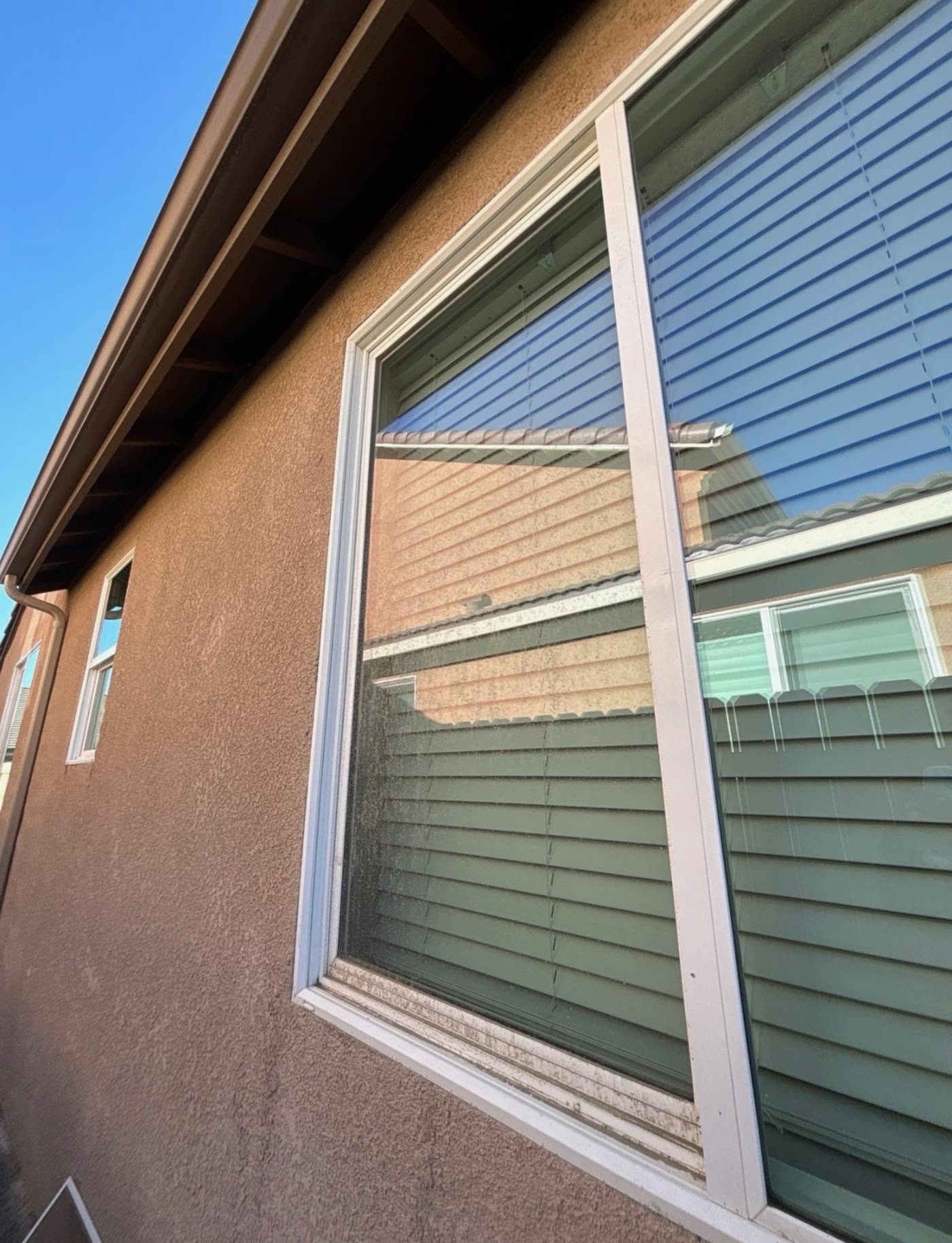 A residential window with hard-water spotting and dust across the exterior glass