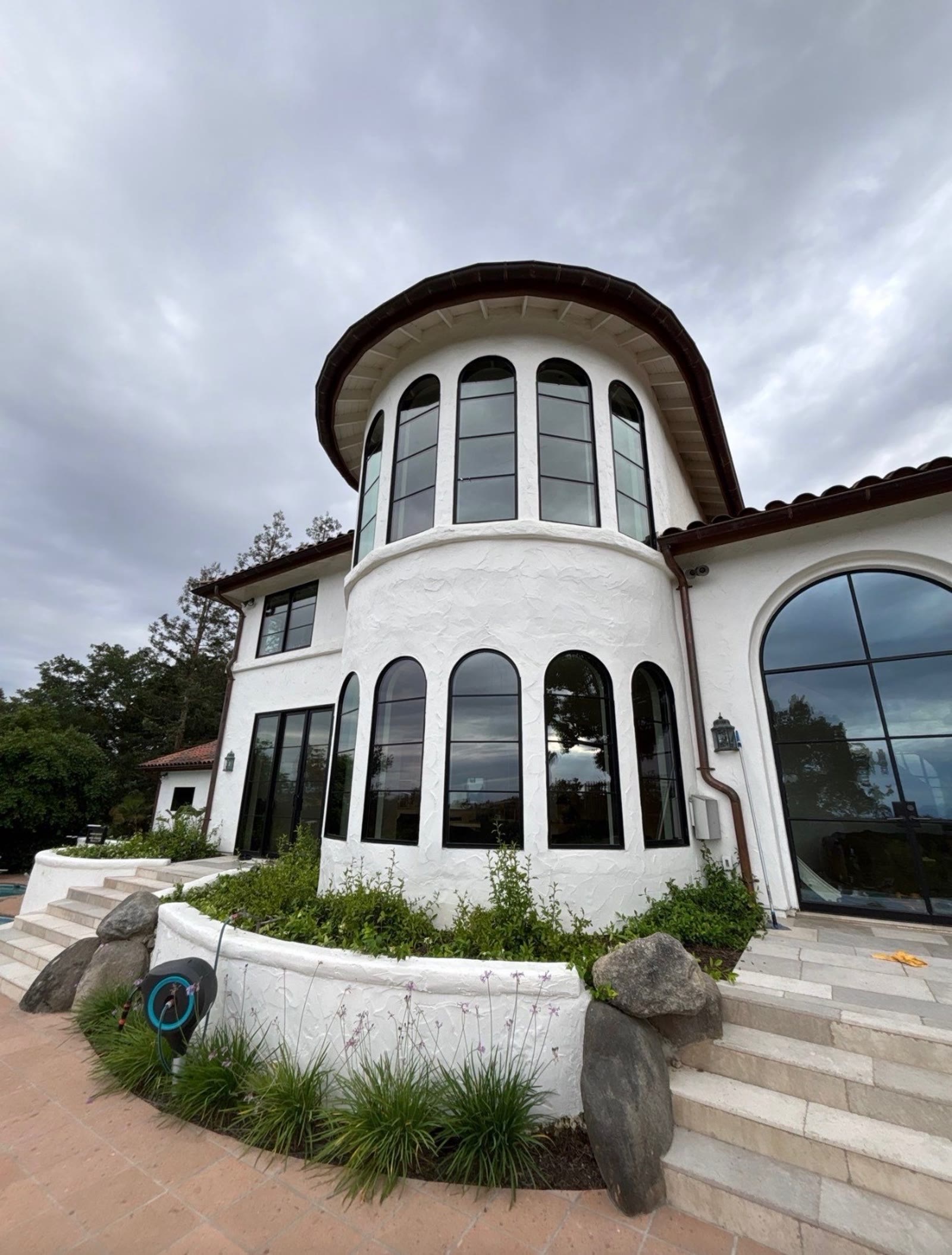 A white stucco two-story home with large windows, cleaned and photographed from the walkway