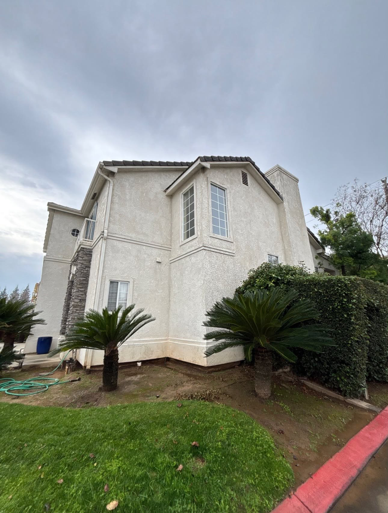 The same two-story stucco home after a full house wash, with clean bright walls and no staining