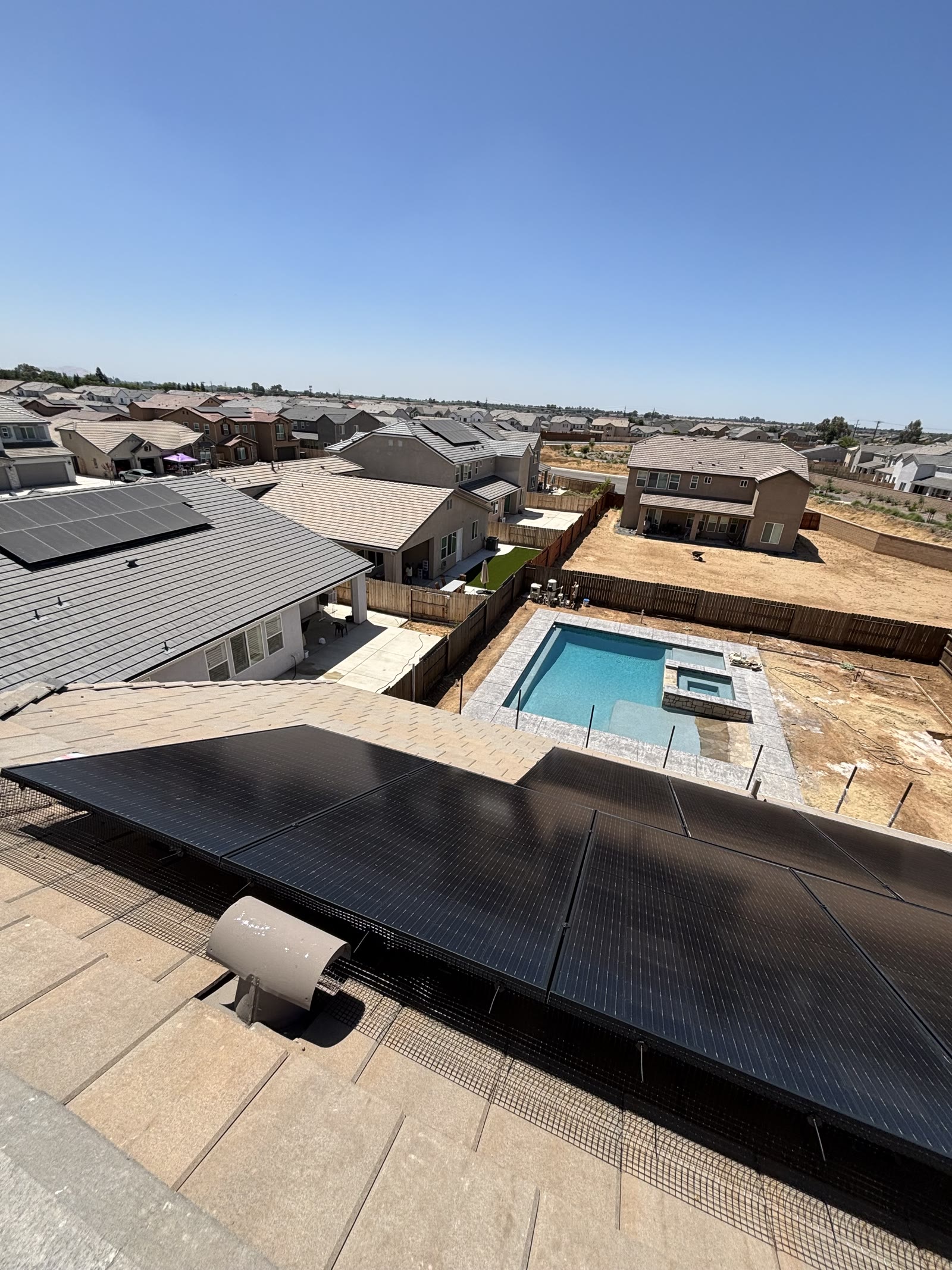 An overhead view of solar panels on a tile roof with bird proofing mesh installed along the panel perimeter