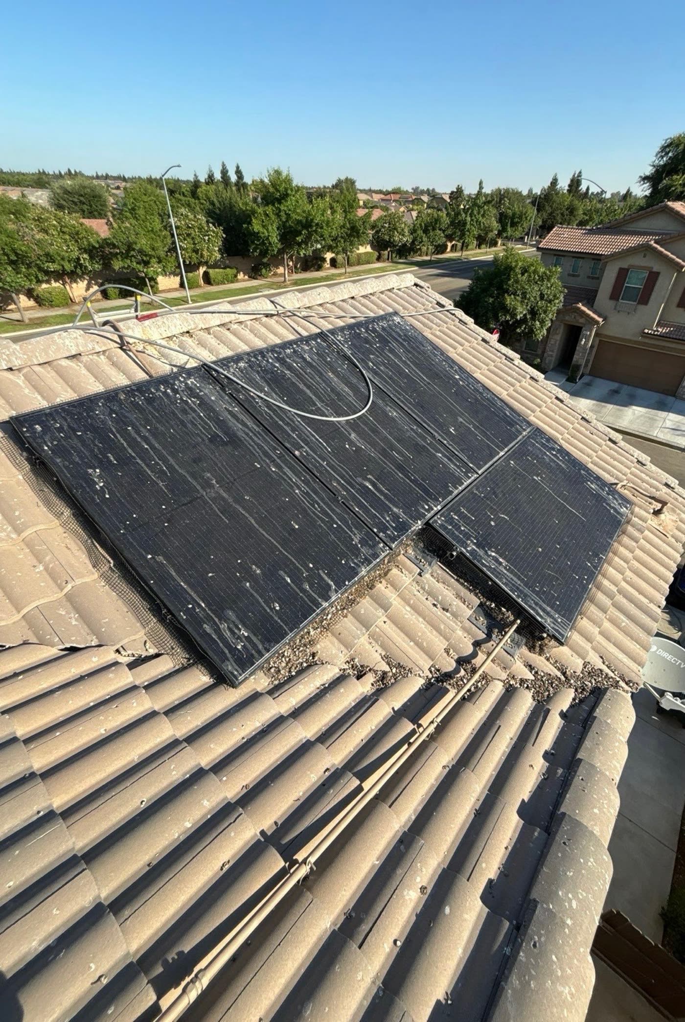 A solar panel on a tile roof covered in dust and debris before cleaning