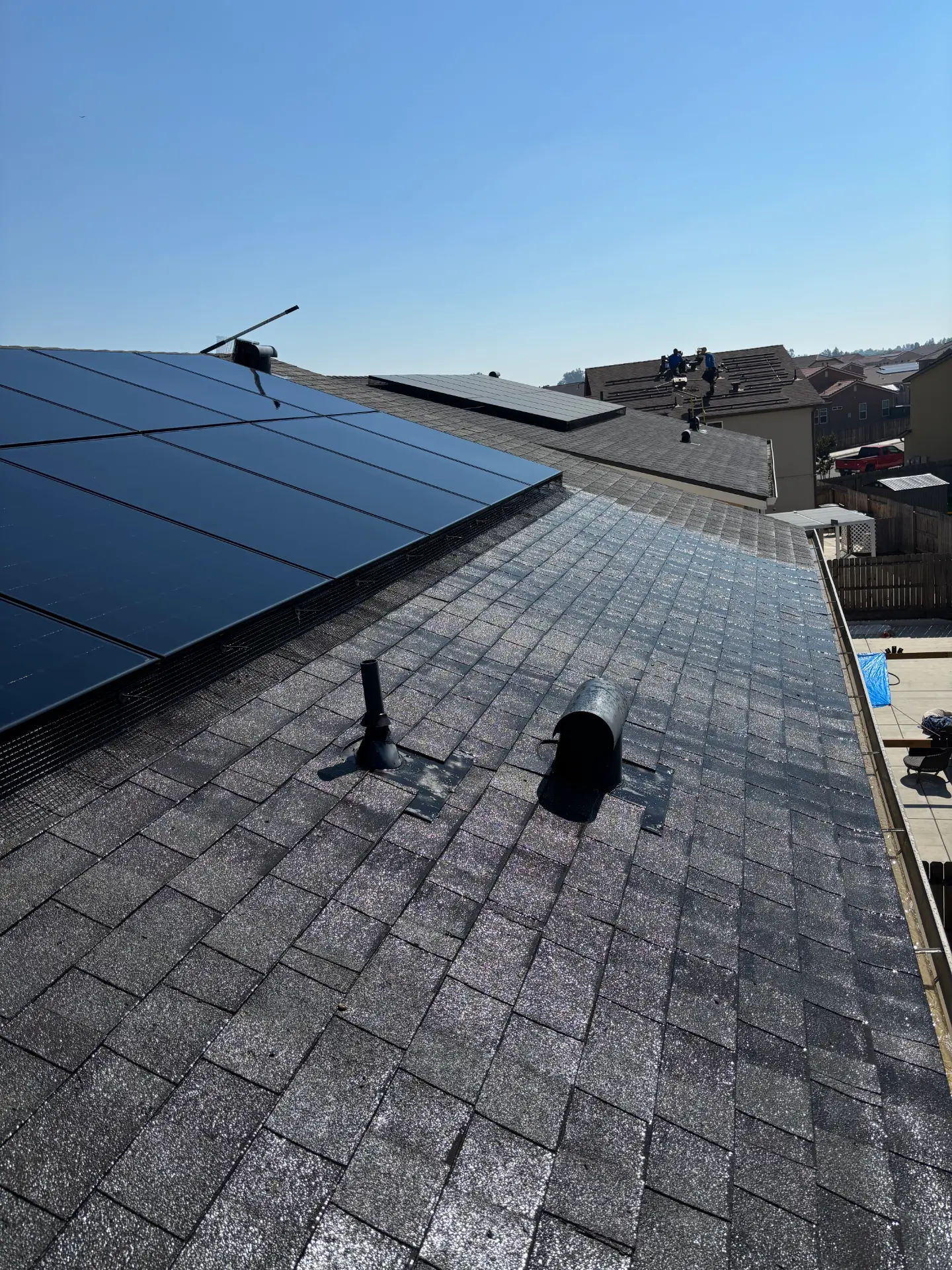 Rooftop solar array edged with black bird-proofing mesh, viewed across clean shingles on a Madera home