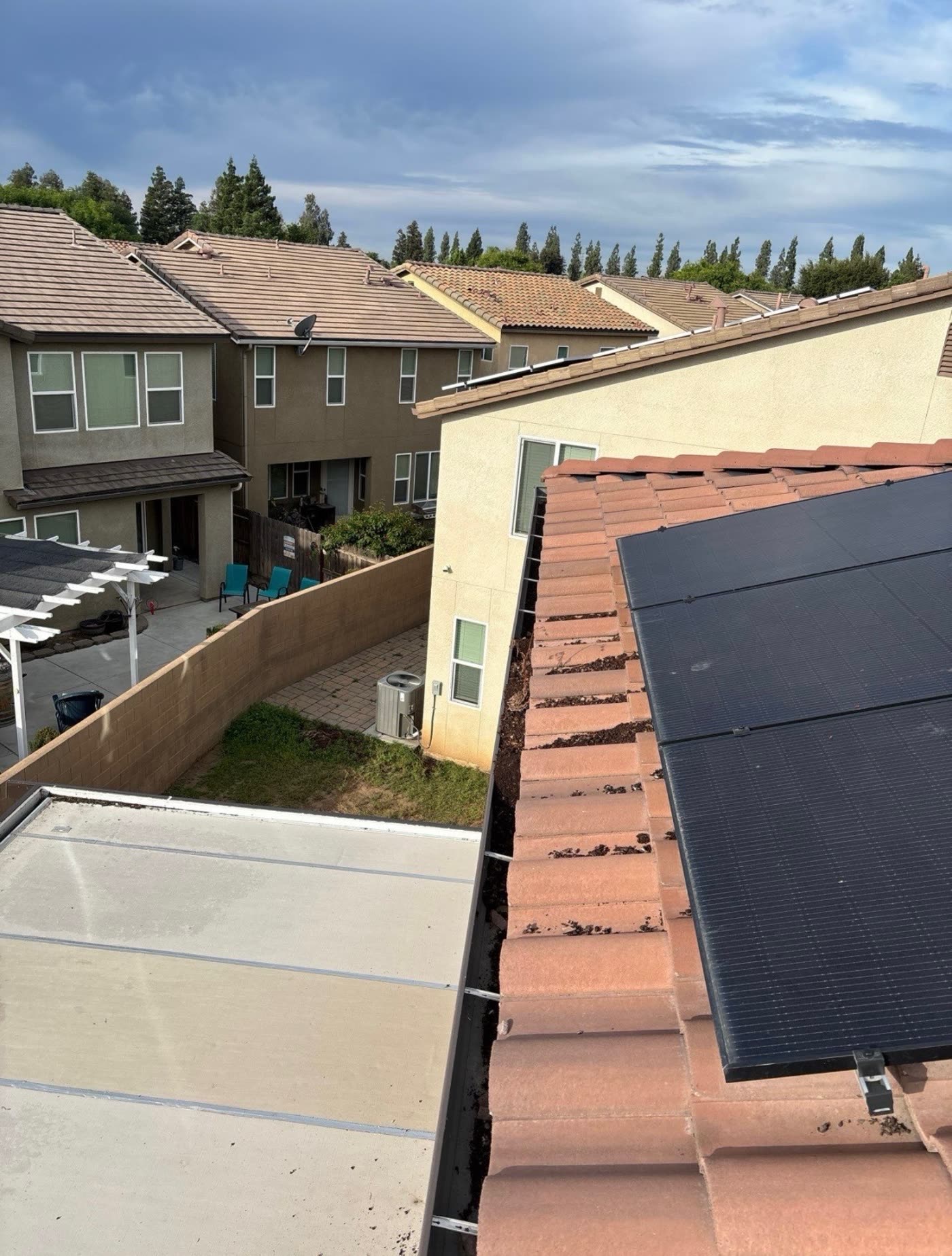 Solar panels on a tile roof before bird proofing, with debris built up along the open gap under the panel edge