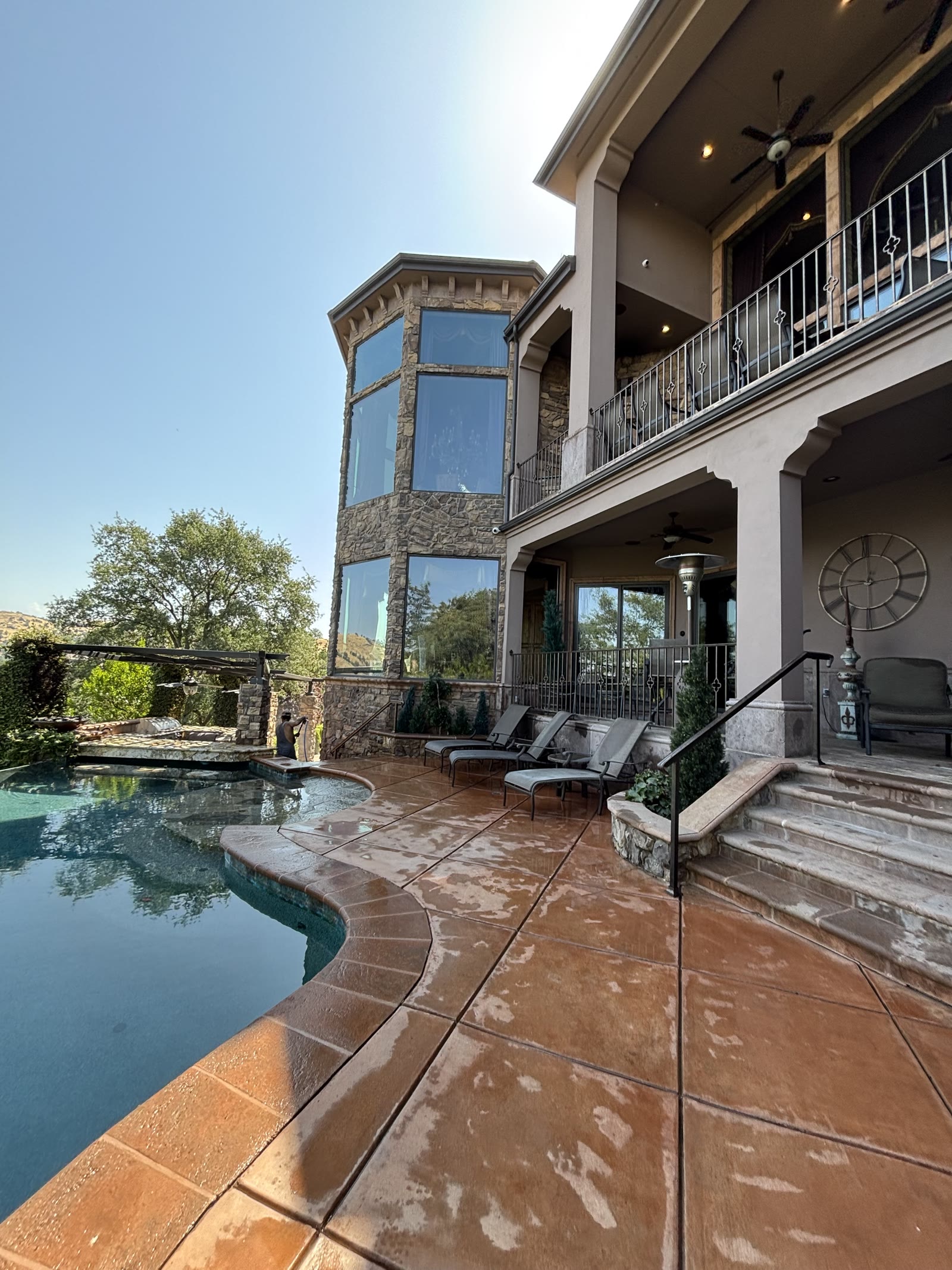 A stamped concrete pool deck and stone patio washed clean beside a swimming pool